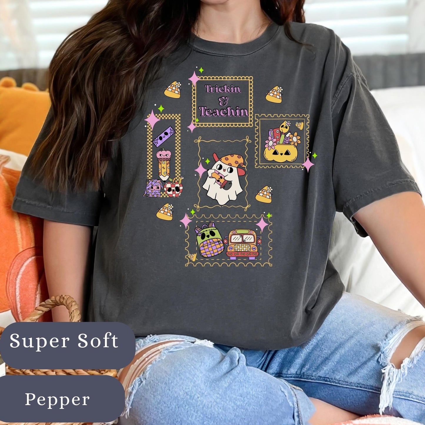 Women’s pepper grey t-shirt with the phrase trickin and teaching has teacher accessories in a stamp frame spooky halloween themed.