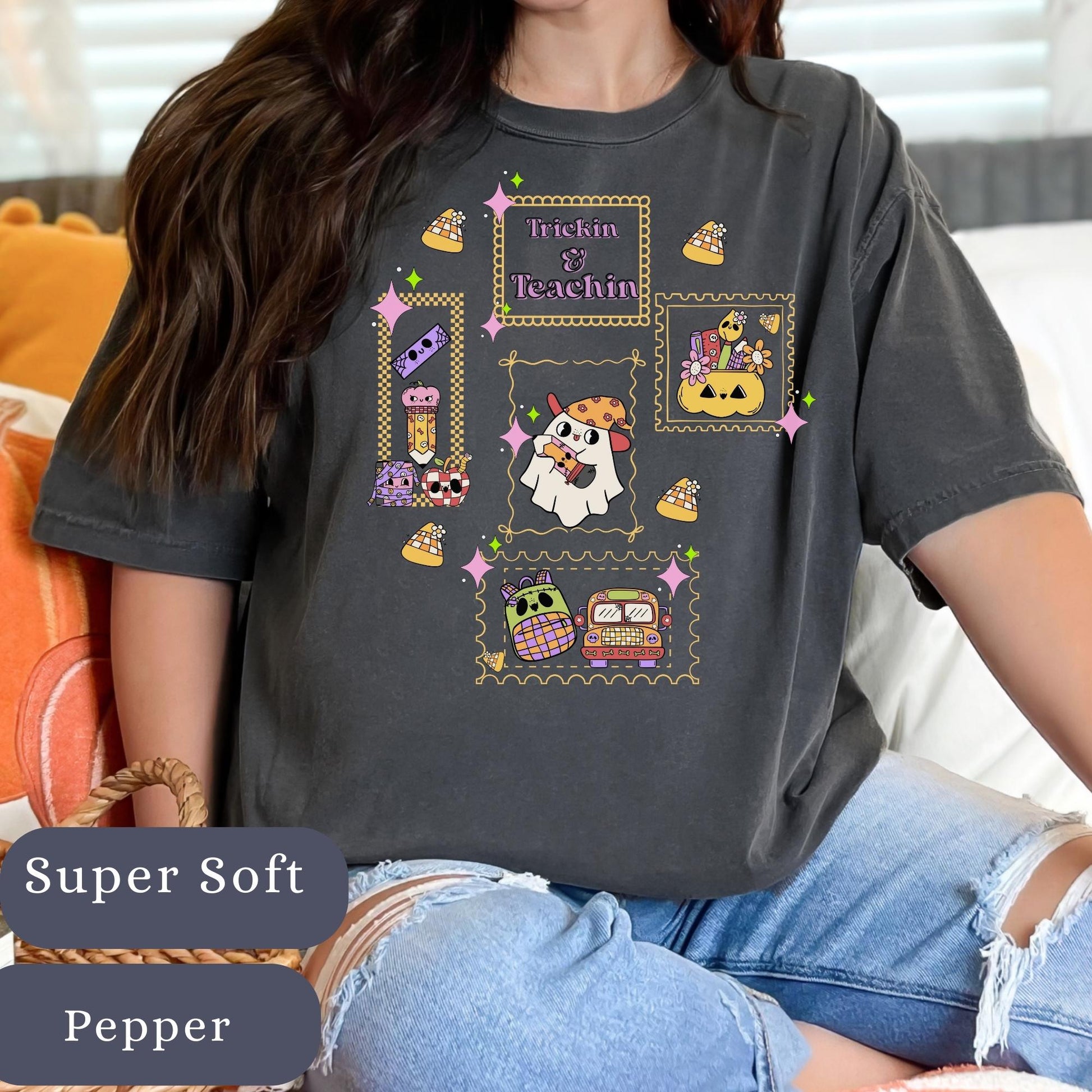 Women’s pepper grey t-shirt with the phrase trickin and teaching has teacher accessories in a stamp frame spooky halloween themed.